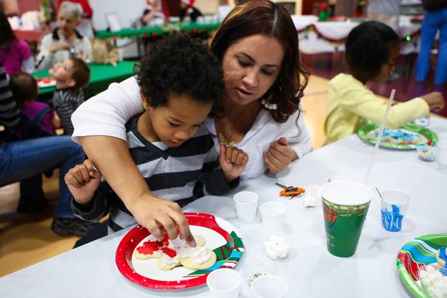 Anthony Cherry, 5, receives a little help from his mom, Regina Zamora, while making his gingerbread man at the "We Knead the Dough" festival at Faith Lutheran School campus Saturday, December 8, 2012.